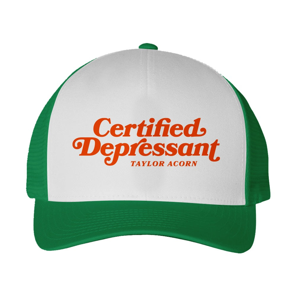 A green and white Taylor Acorn trucker hat featuring “Certified Depressant” and “Taylor Acorn” in bold orange letters on the front panel.