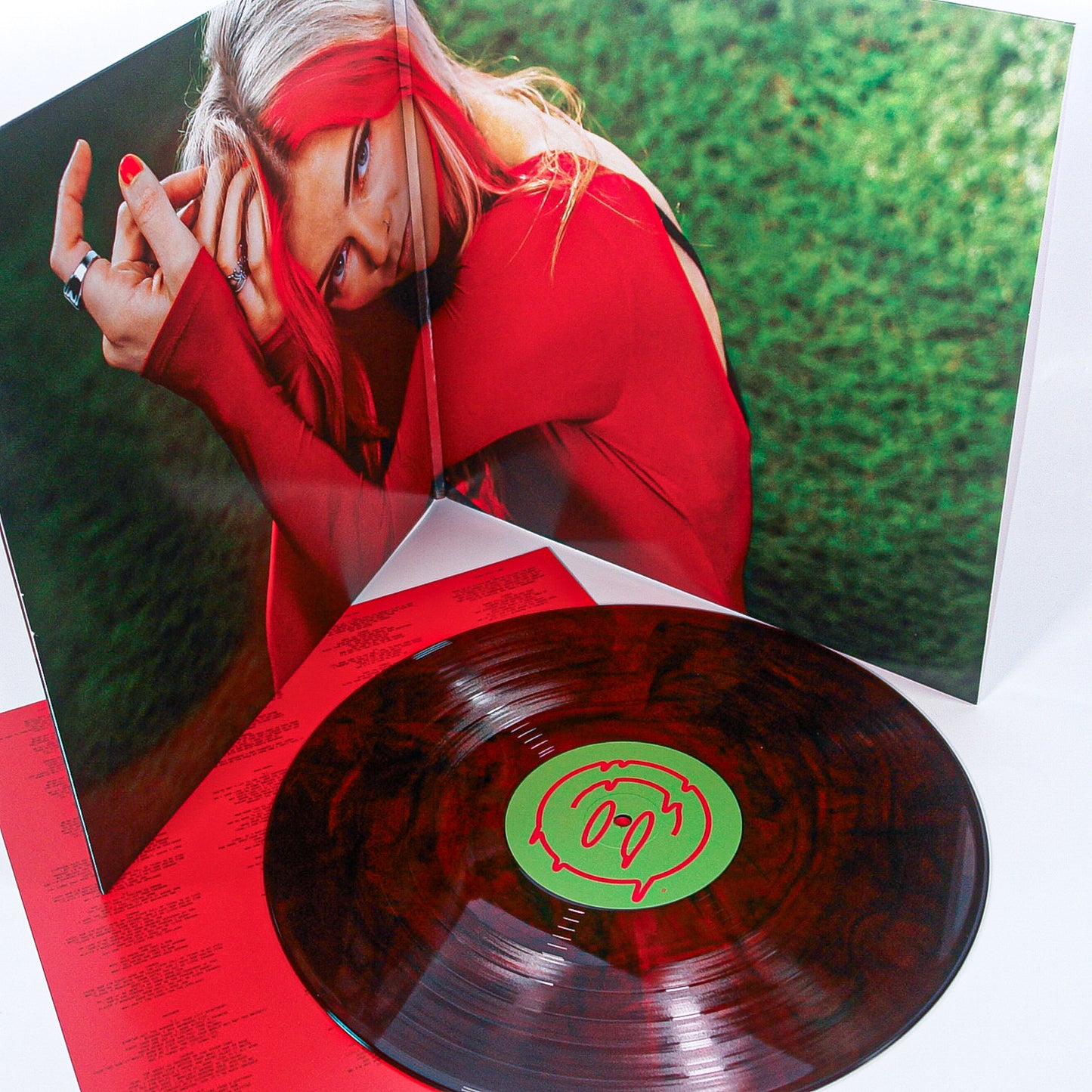A marbled Candy Corn LP rests on a red lyric sleeve before a gatefold album cover of Taylor Acorn, showing her with long blonde and pink hair, wearing red and posing with arms raised against a green background.
