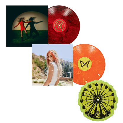 Two vibrant Taylor Acorn vinyl records with unique album covers—one shows two women running in shadows, another features a woman outdoors. Also included is a yellow Candy Corn LP shaped like a Ferris wheel in a gatefold jacket.