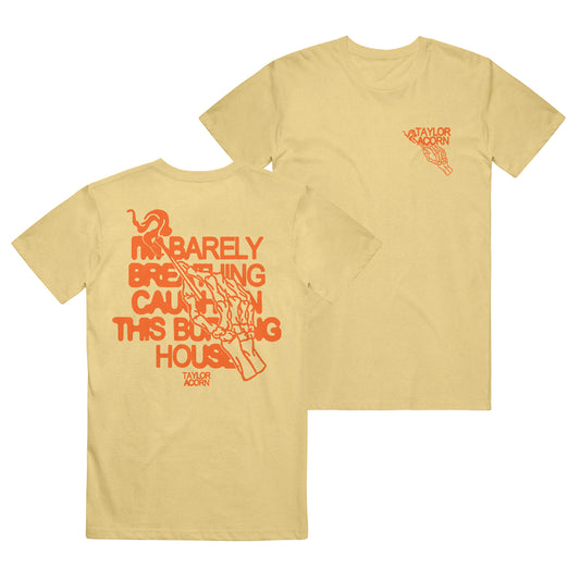 Taylor Acorn yellow Comfort Colors tee featuring orange text and graphics: large back print reads “I’m barely breathing caught in this burning house” with a hand holding a match; small Taylor Acorn logo on the front.